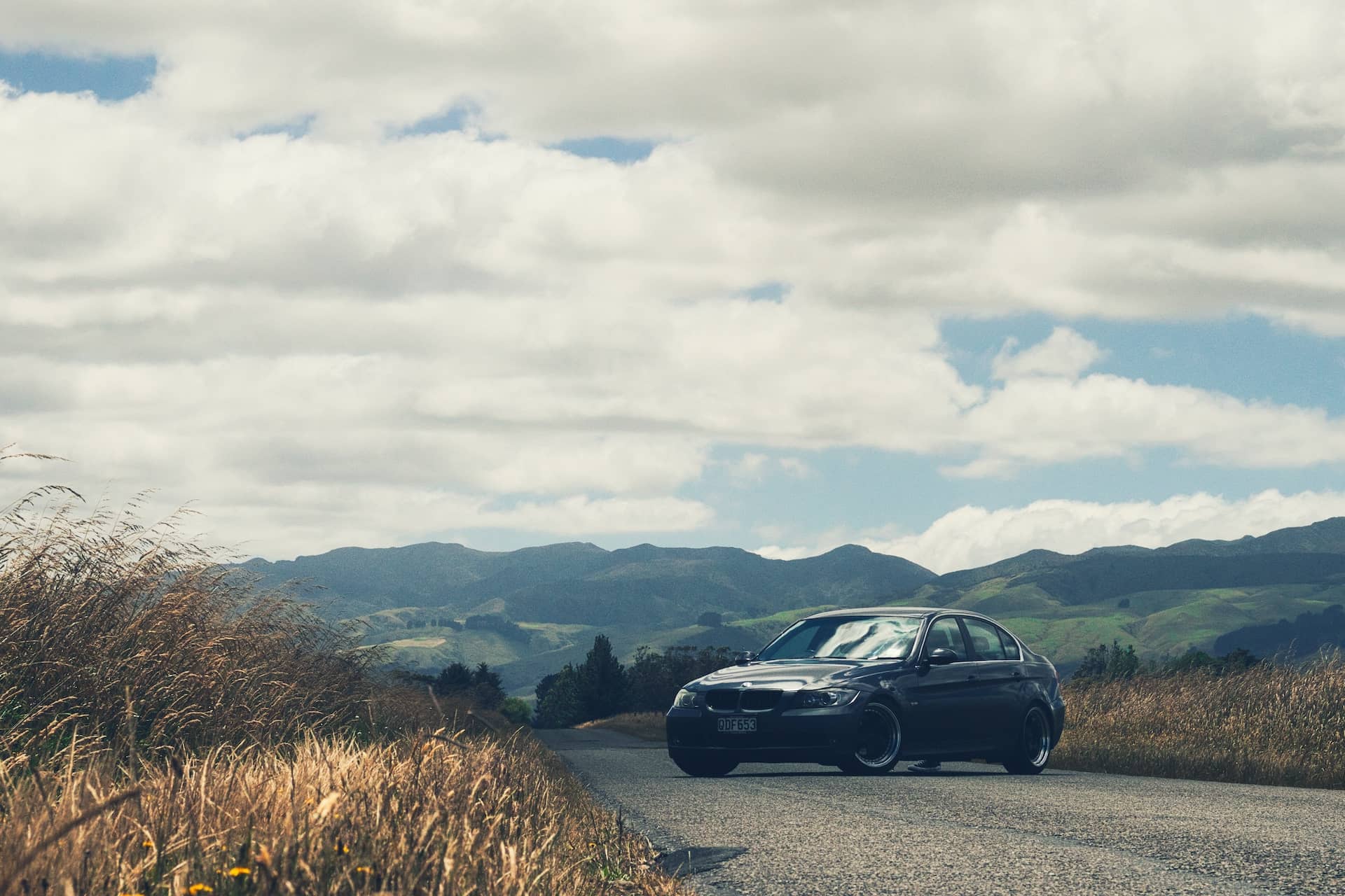 Picture of a dark grey BMW on a remote country road.