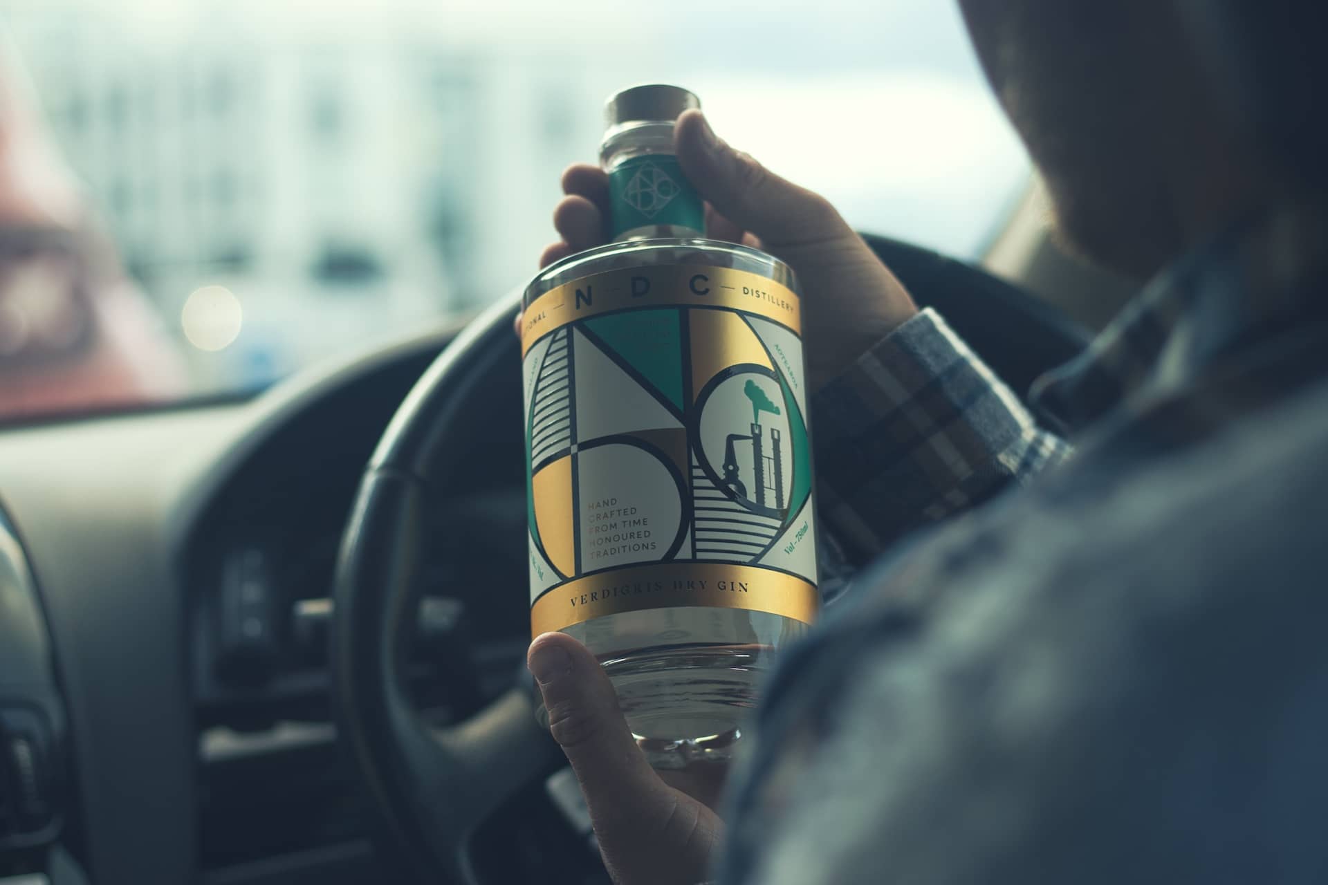 Photo of a man holding a bottle of verdigris dry gin from the National Distillery Company.