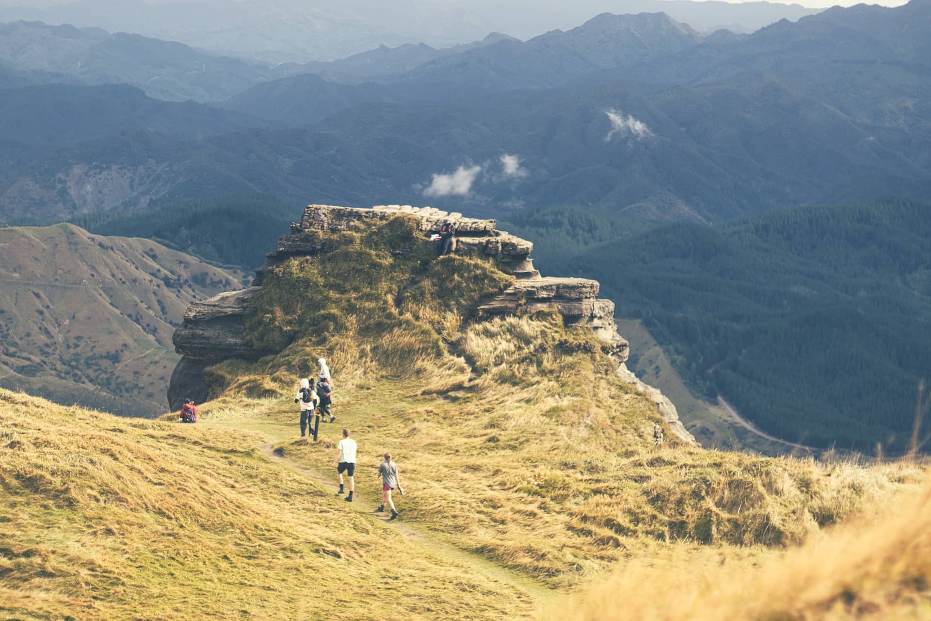 Photo of a large rock formation, with travellers heading towards it.